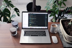 macbook pro beside white ceramic mug on brown wooden table