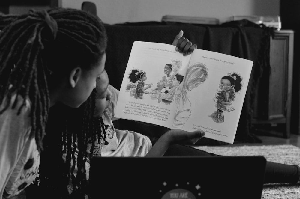 Foto en escala de grises de niño sosteniendo un libro