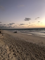 A serene beach scene at sunset, where an expat is journaling about their new life abroad.