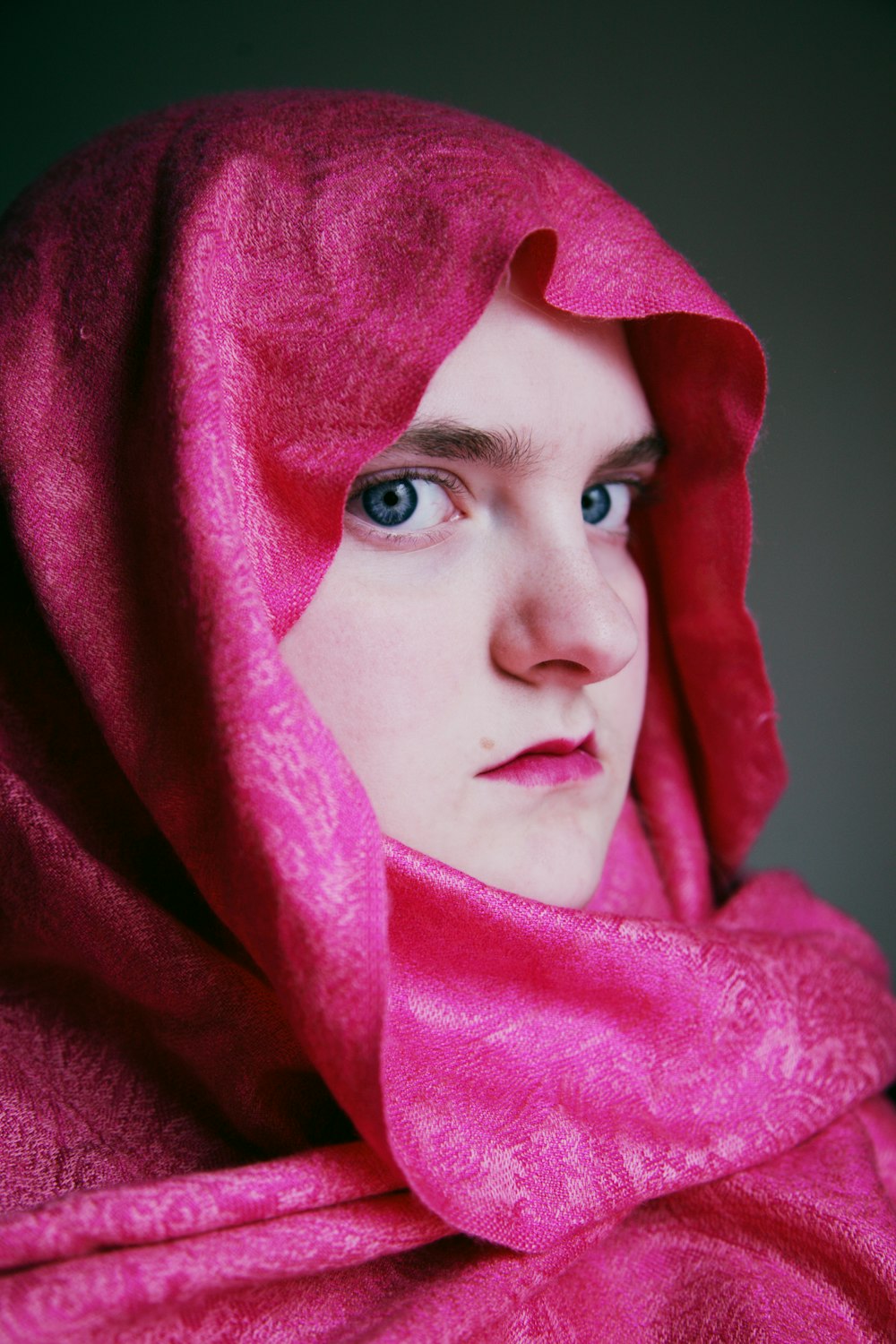 donna in hijab rosa che si copre il viso con tessuto viola