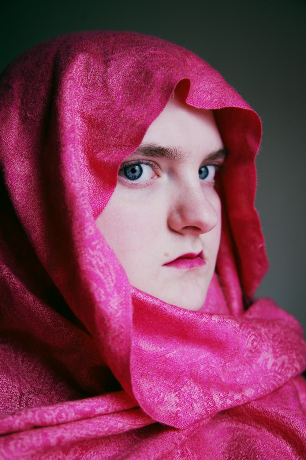 woman in pink hijab covering her face with purple textile