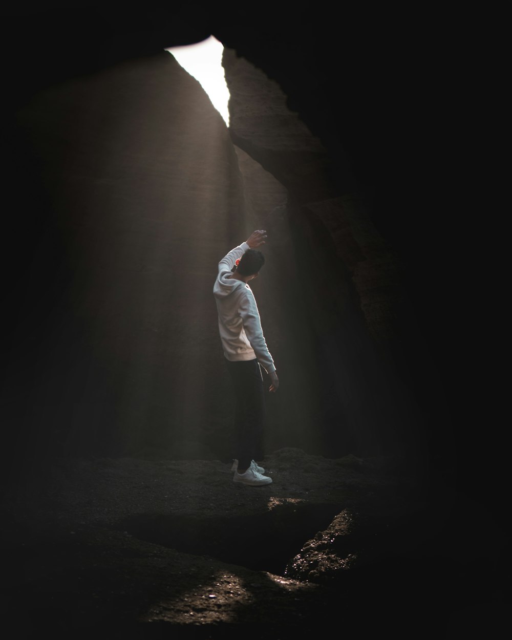 man in white long sleeve shirt and white pants standing on rock