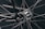 A close-up view of a bicycle wheel focusing on the hub and spokes. The metallic spokes radiate from the central hub, which is intricately designed and features visible screws and a rotating mechanism. The chain and part of the frame are also visible, demonstrating precision engineering and craftsmanship.