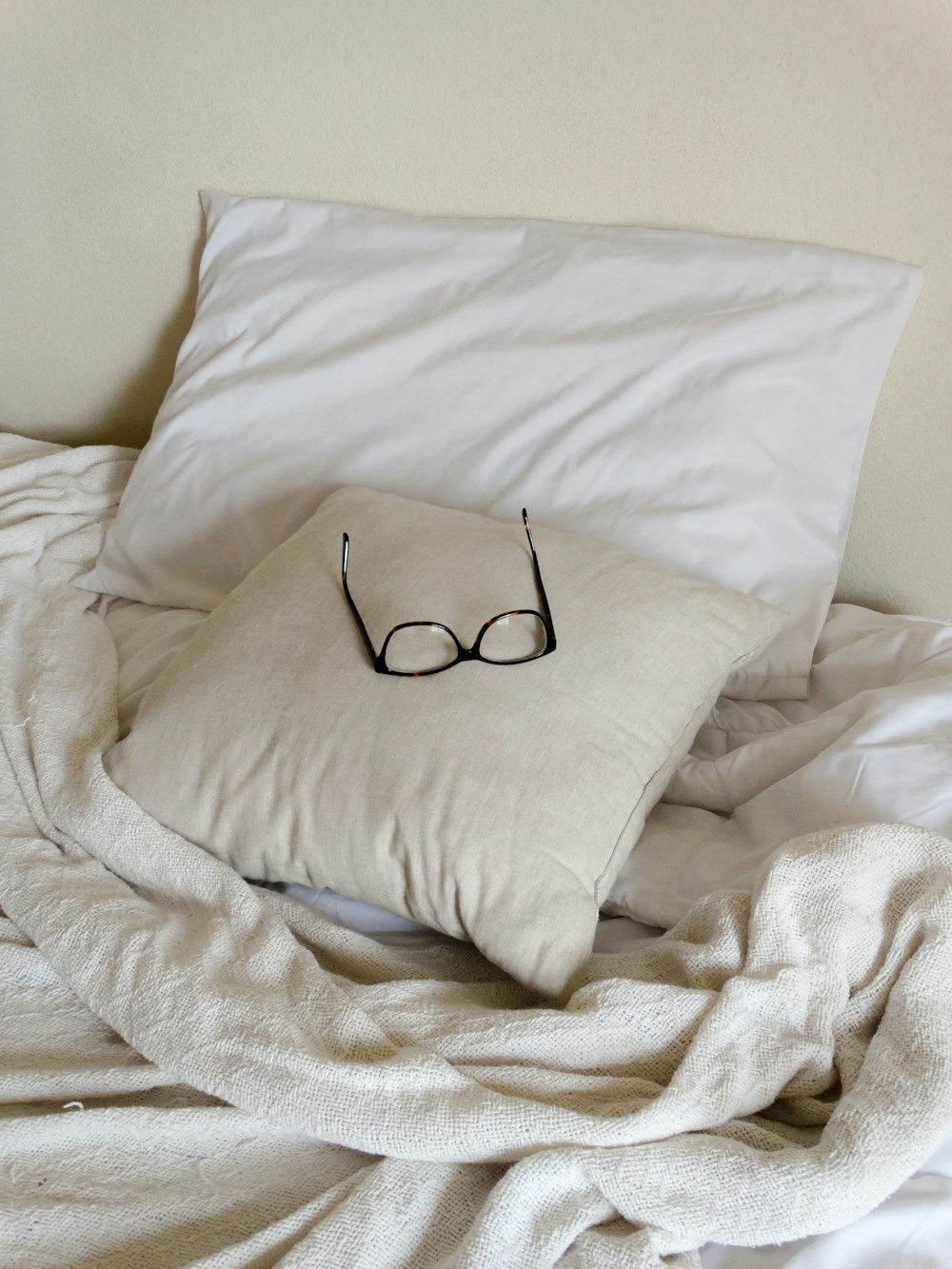 black framed eyeglasses on white throw pillow
