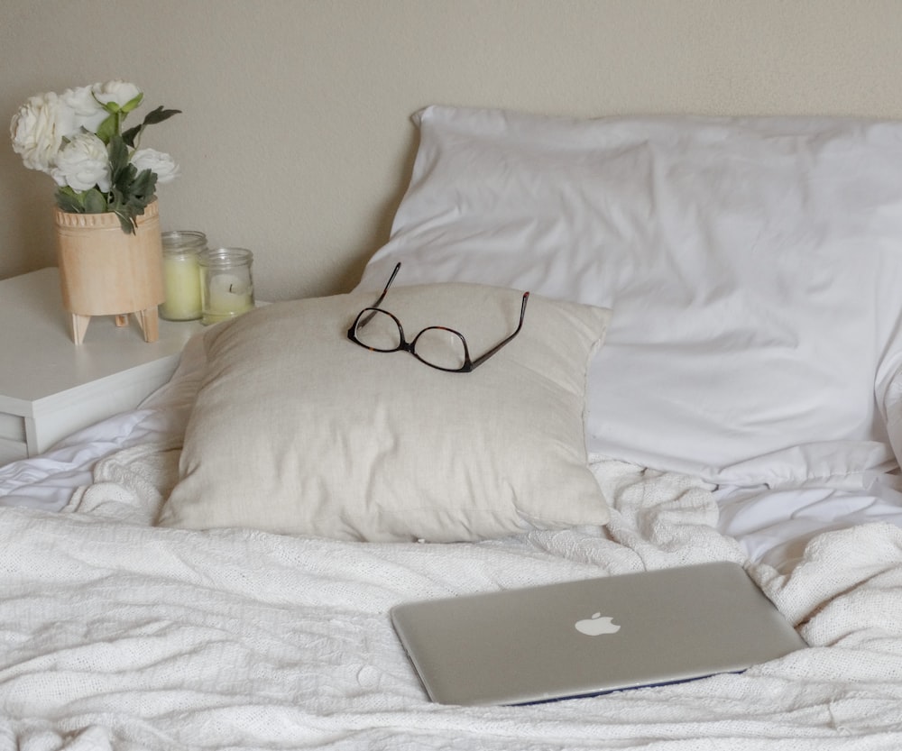 silver macbook on white bed