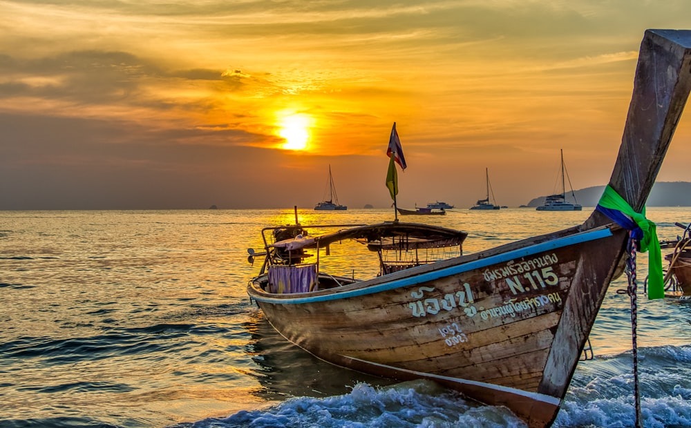 brown and white boat on sea during sunset