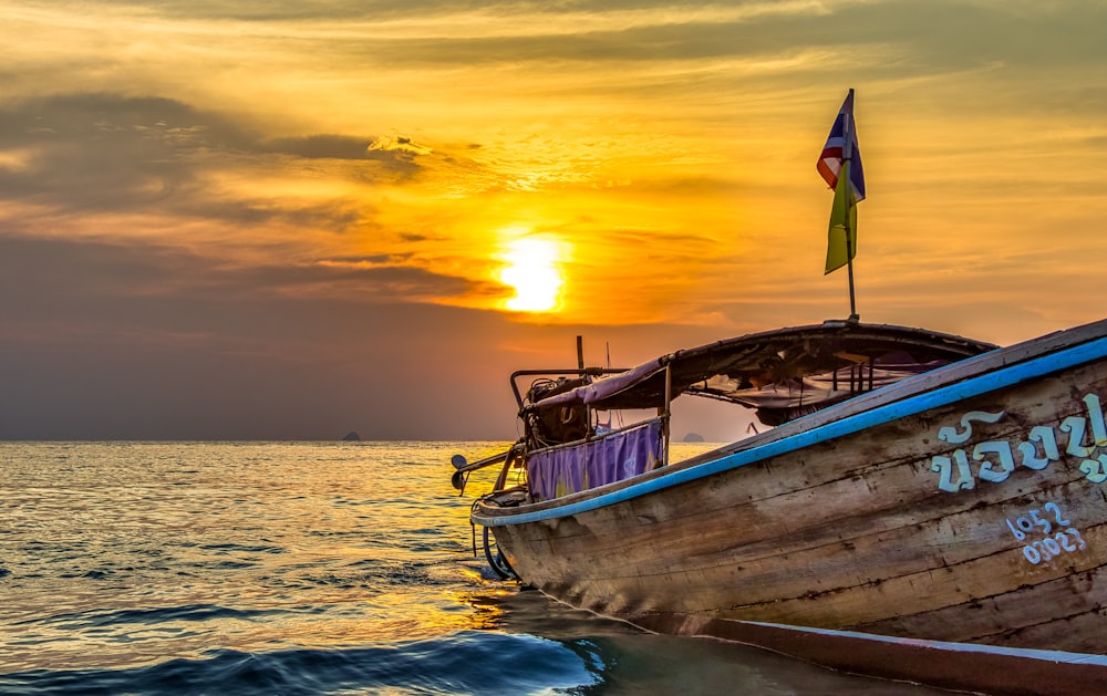 weißes und braunes Boot auf See bei Sonnenuntergang