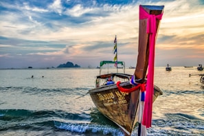 A traditional wooden boat sailing near Komodo Island at sunset with vibrant orange skies.