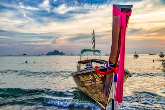 A traditional wooden boat sailing near Komodo Island at sunset with vibrant orange skies.