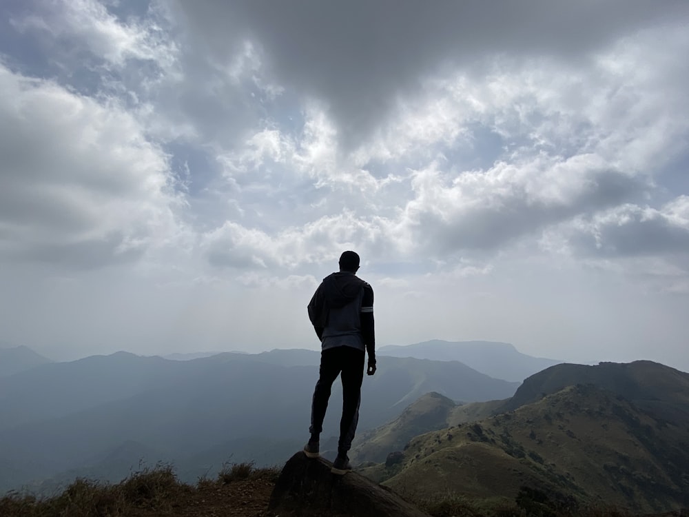 man in black jacket standing on rock formation during daytime