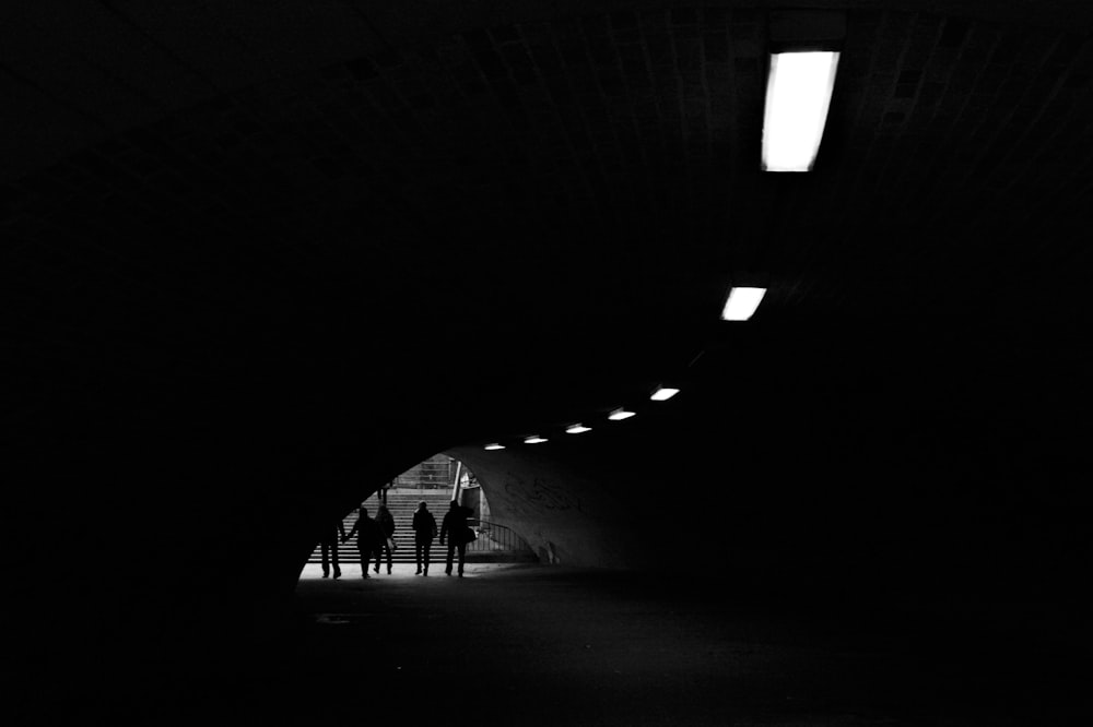 silhouette of people walking on tunnel