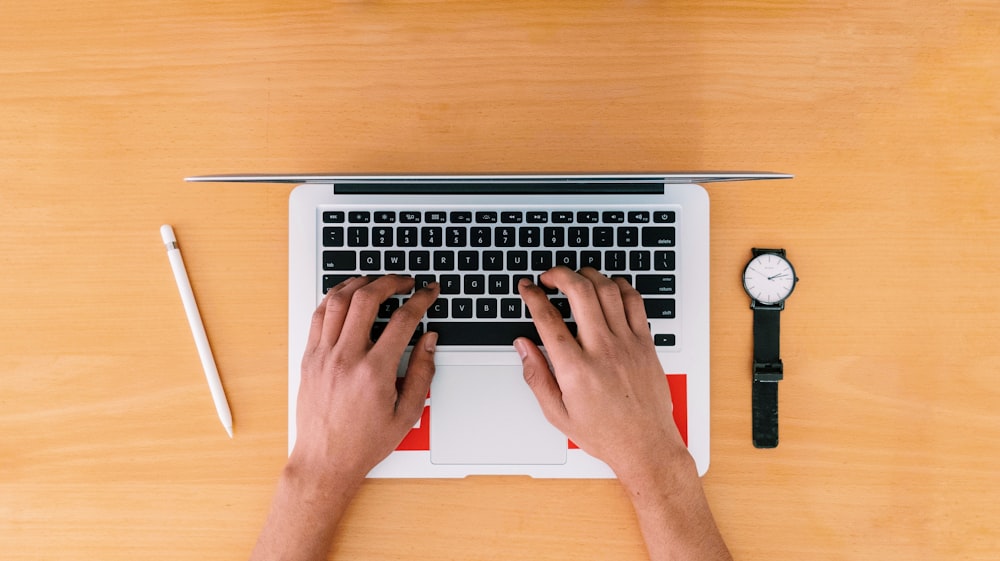 person using macbook pro on brown wooden table