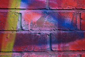 A skilled artist printing a colorful mural directly onto a textured brick wall outdoors.