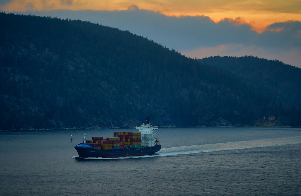 blue and white ship on sea near green trees during daytime