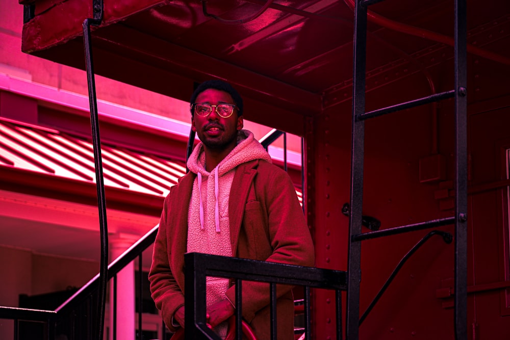 man in red long sleeve shirt standing beside red metal frame