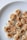 Slices of banana topped with peanut butter and sprinkled with black and white sesame seeds on a white plate.