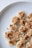 Slices of banana topped with peanut butter and sprinkled with black and white sesame seeds on a white plate.
