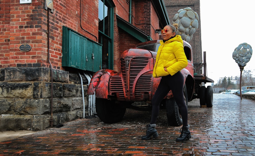 woman in yellow hoodie standing beside red car