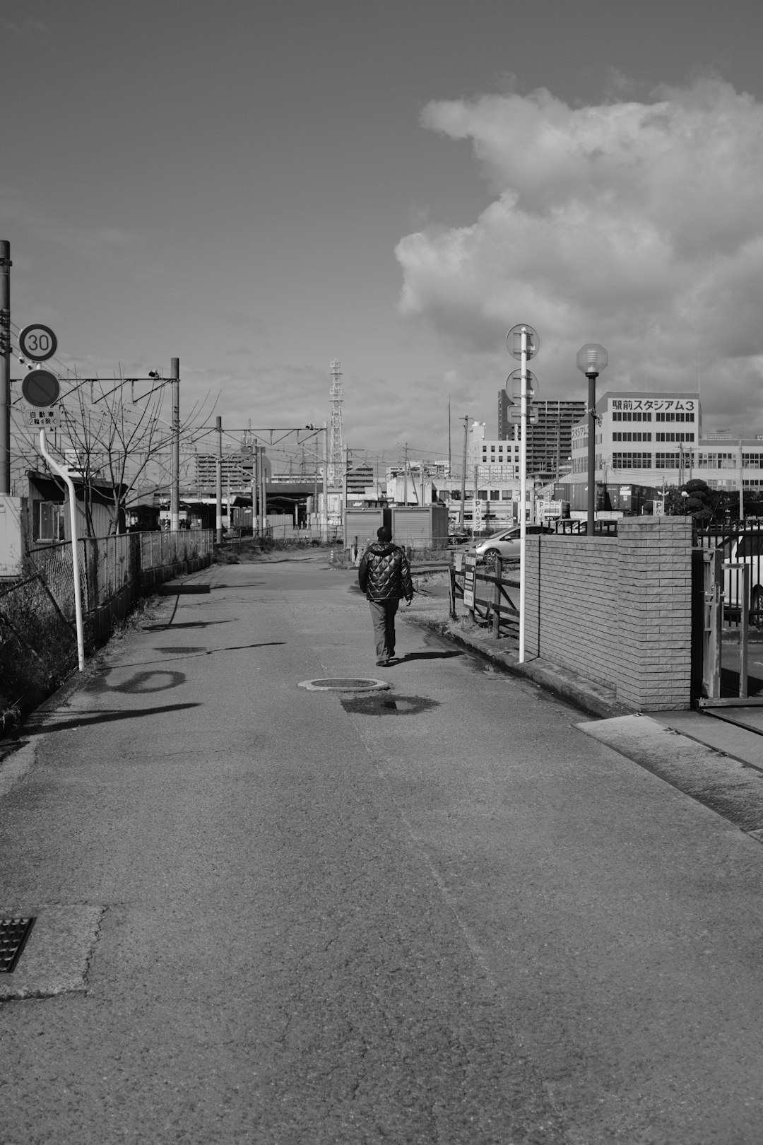 grayscale photo of woman walking on sidewalk