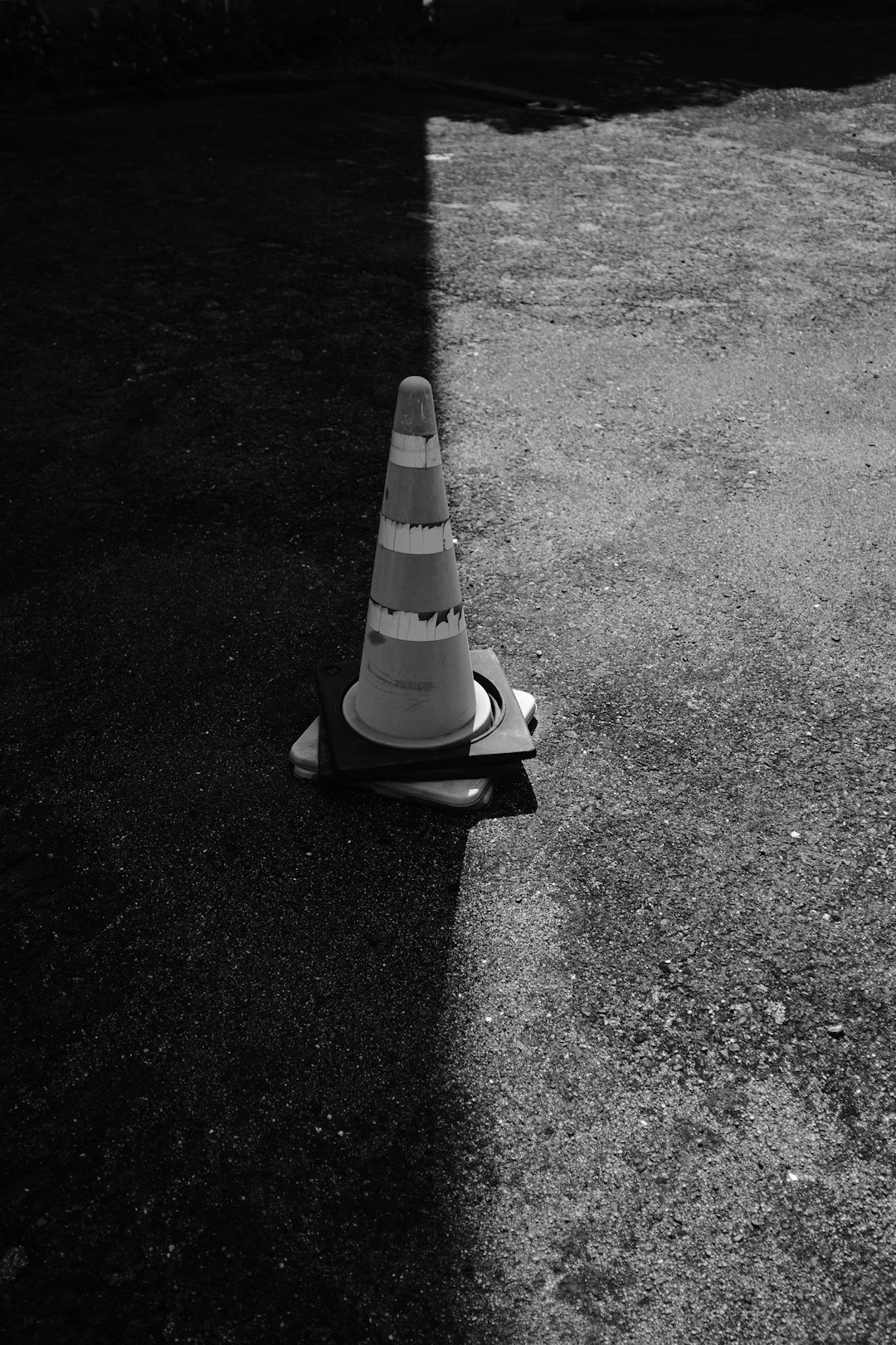 white and black striped traffic cone on black asphalt road