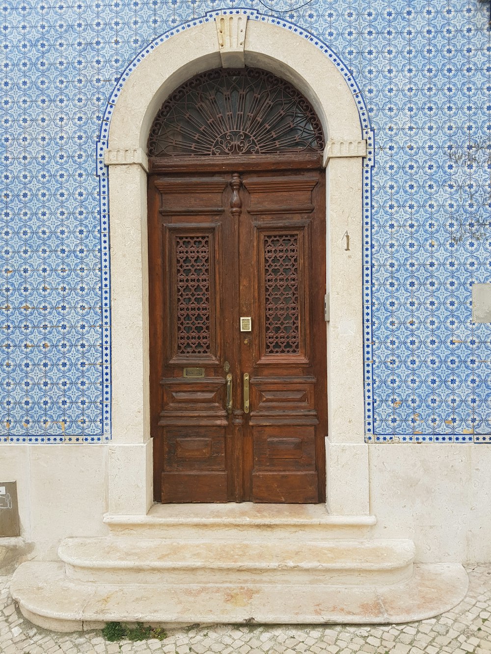 brown wooden door on blue and white floral wall