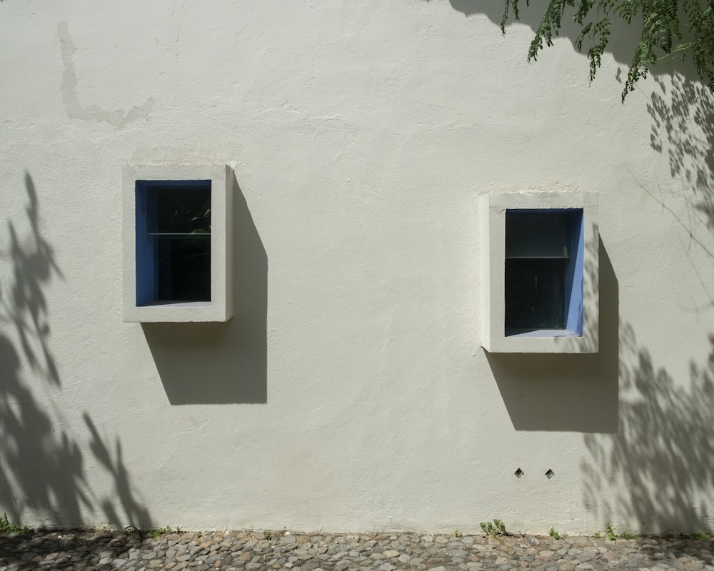 白いコンクリートの壁に青い木製の窓