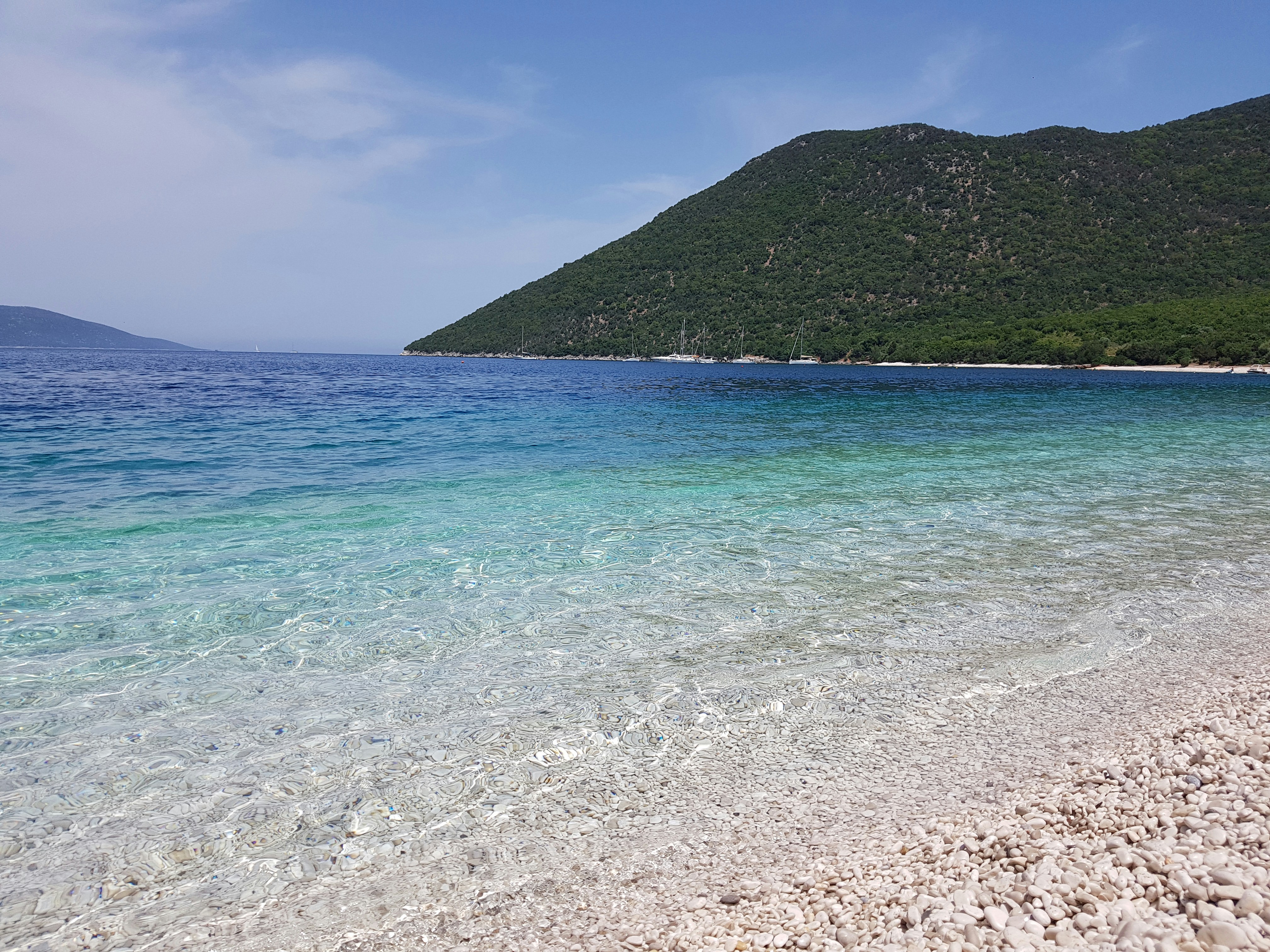 green mountain beside blue sea under blue sky during daytime, Pebble beach in Greece