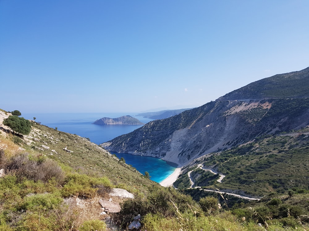 green mountain near blue sea under blue sky during daytime