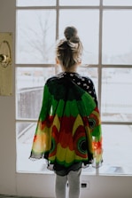 woman in green orange and yellow dress standing near window