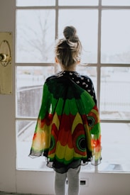 woman in green orange and yellow dress standing near window