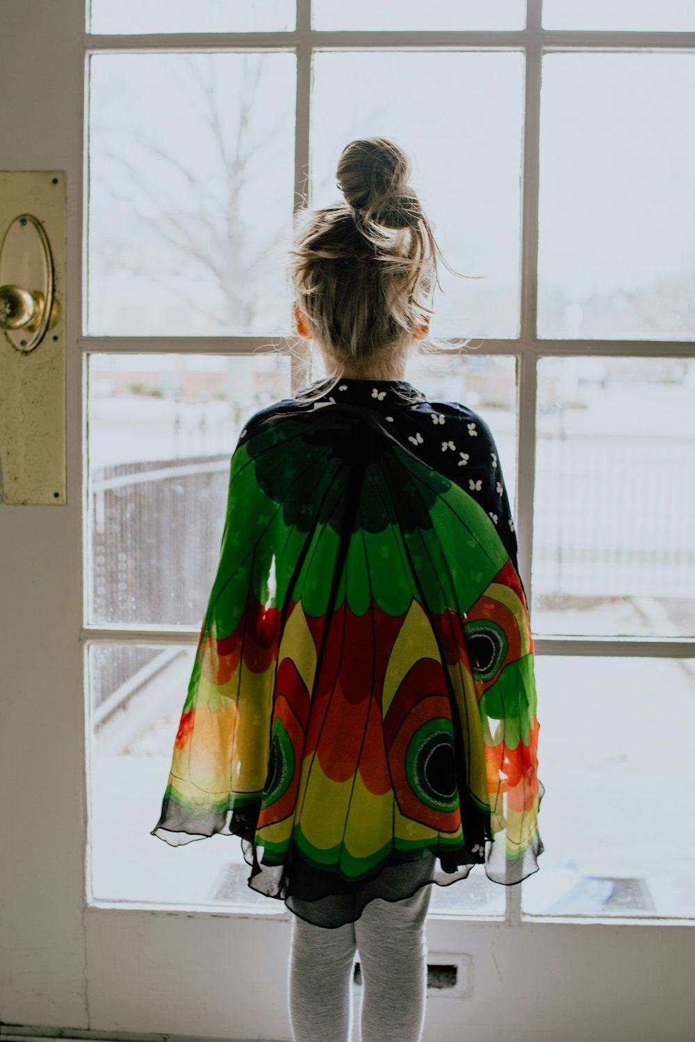 woman in green orange and yellow dress standing near window