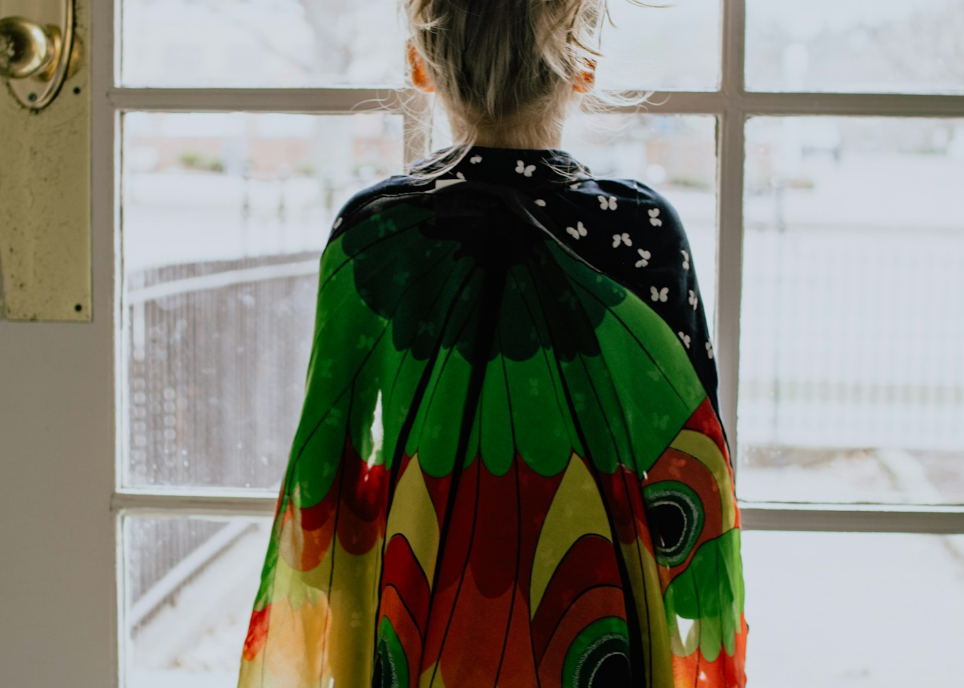 woman in green orange and yellow dress standing near window