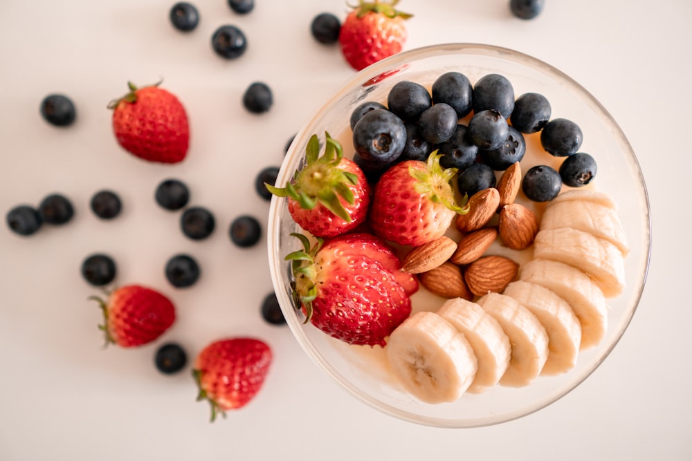 sliced strawberries and blueberries in clear glass bowl