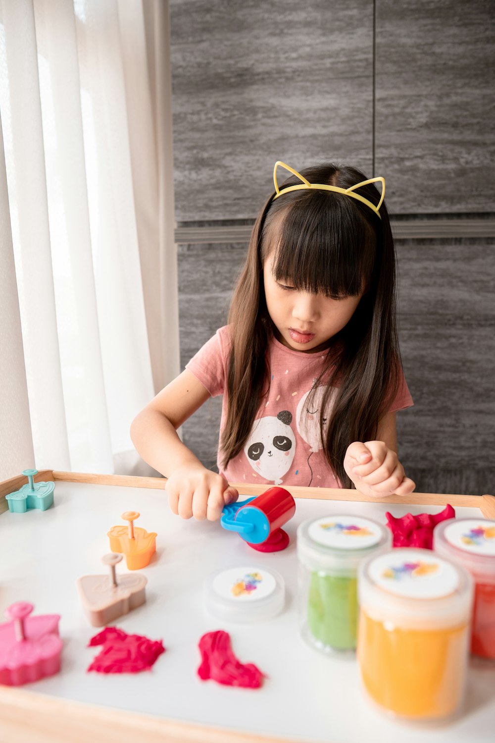 girl in pink and white stripe t-shirt playing with plastic toys