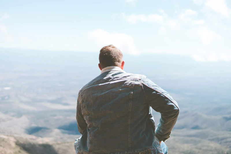 UK sugar daddy in a gray dress shirt standing on the seashore