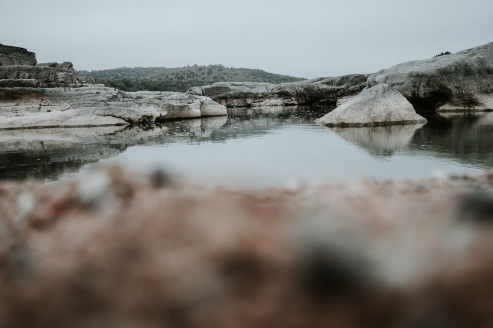 Braune und graue Felsformation am See tagsüber