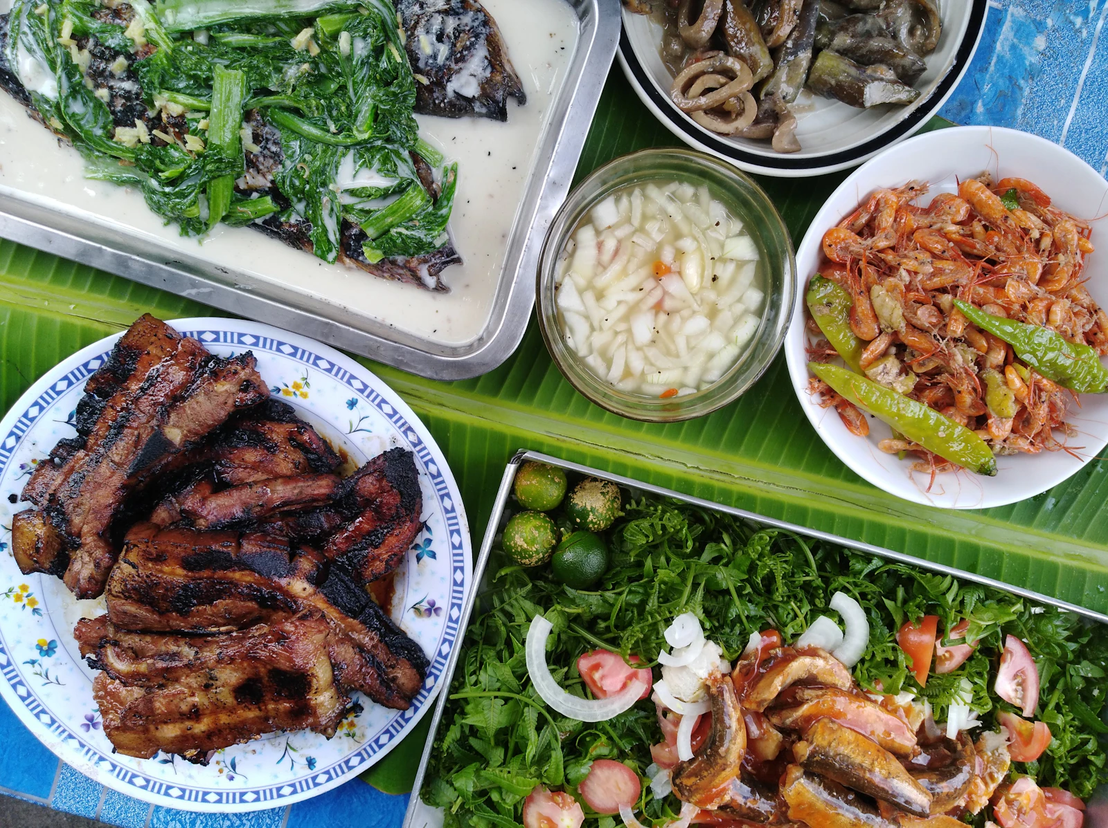 A spread of Filipino dishes for sharing, laid out on a banana leaf