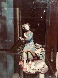 Close-up of a delicate, hand-painted ceramic figurine resting on a velvet cloth.