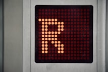 A digital display panel features a large orange letter 'R' made up of illuminated dots against a dark background. The panel is bordered by a metallic frame.