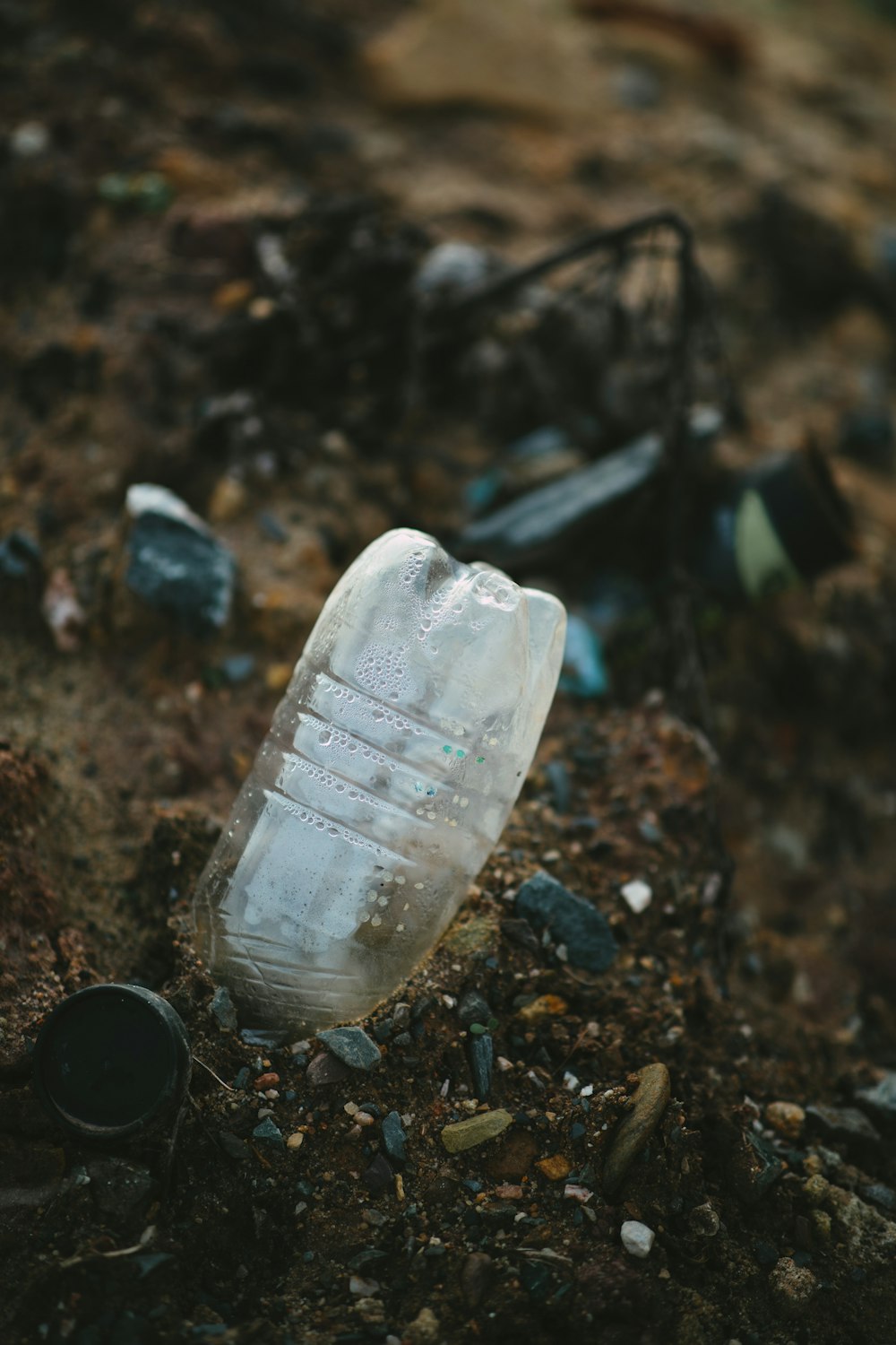 Botella de plástico blanca sobre tierra marrón