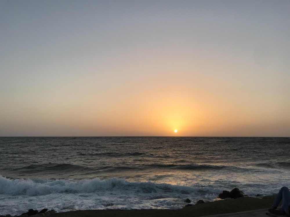 ocean waves crashing on shore during sunset