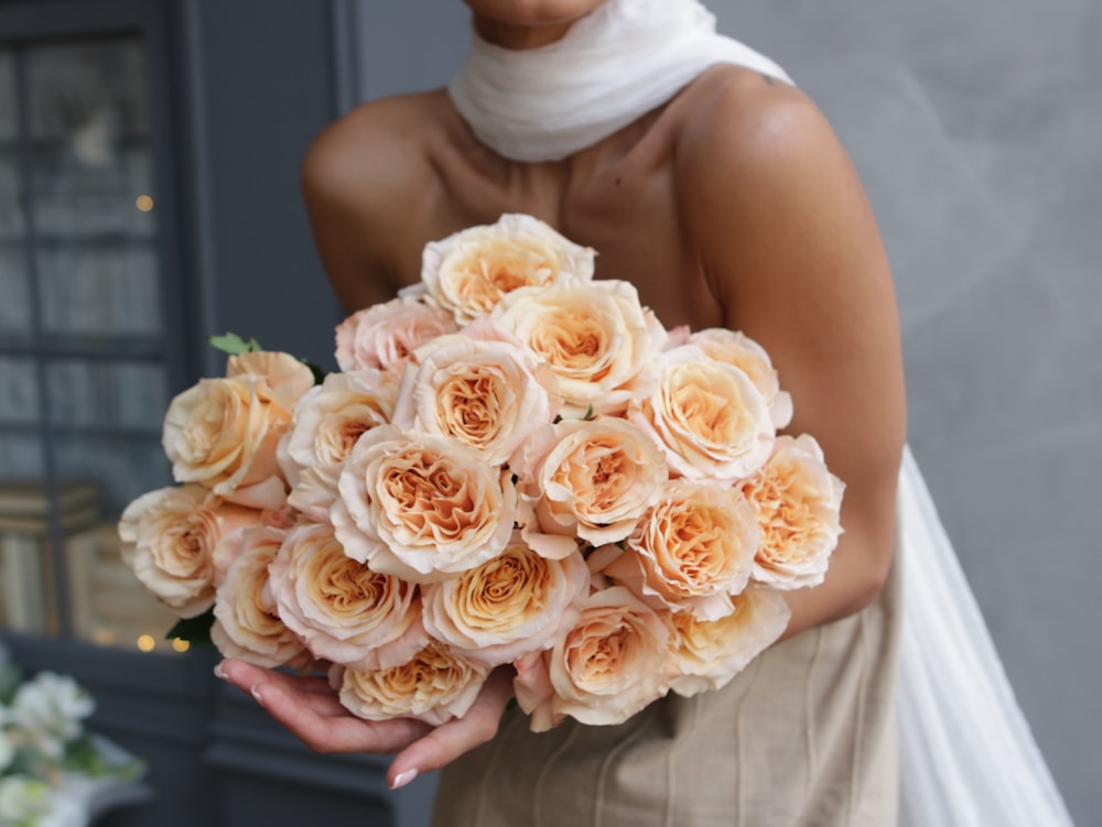 Mujer en vestido de tubo blanco sosteniendo ramo de flores blancas