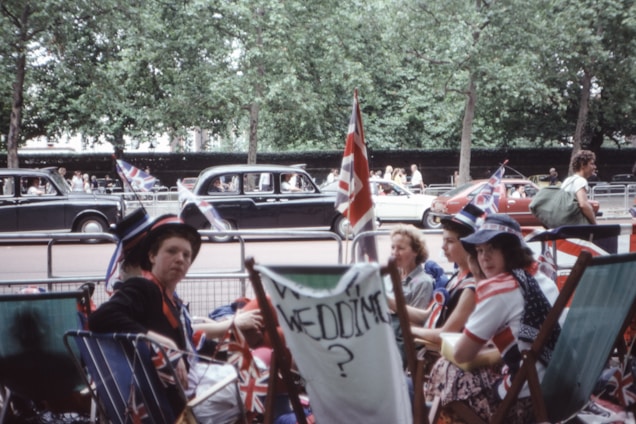 A lively group of friends gathered in a cozy Riverside backyard, waving UK flags and enjoying British snacks.