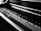 A close-up view of a piano keyboard highlighting the alternating pattern of black and white keys, with light reflecting off the polished surface.