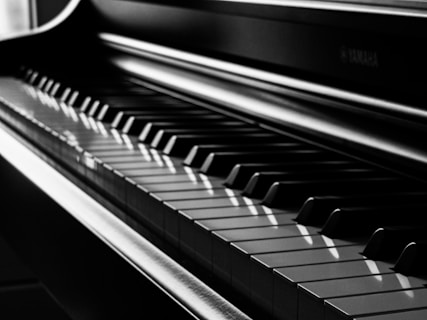 A close-up view of a piano keyboard highlighting the alternating pattern of black and white keys, with light reflecting off the polished surface.
