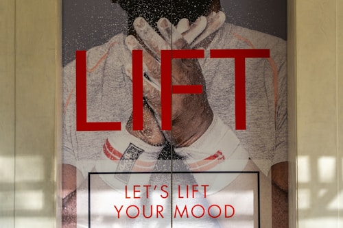 A poster displaying a person wearing white athletic gear, with their hands clasped near their face, and covered in white chalk or powder. The word 'LIFT' is prominently displayed in bold red letters, accompanied by the text 'LET'S LIFT YOUR MOOD' below.