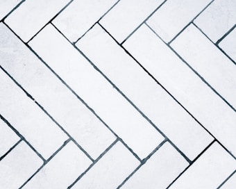 A detailed pattern of light gray tiles arranged in a herringbone design across the surface.