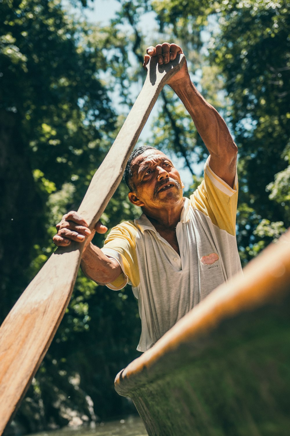 man in gray crew neck t-shirt holding brown wooden stick