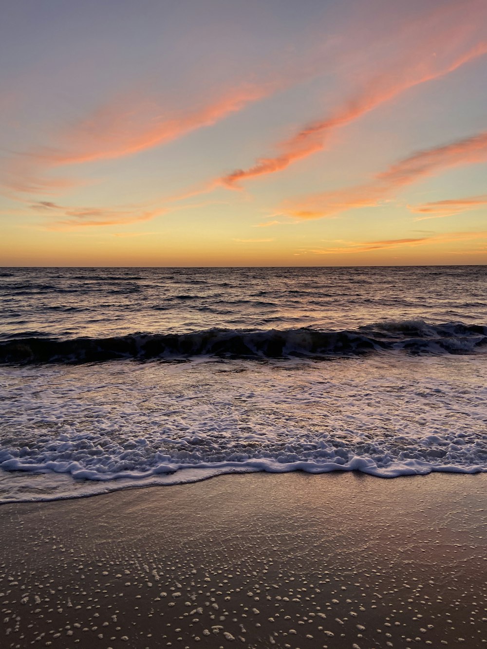 ocean waves crashing on shore during sunset