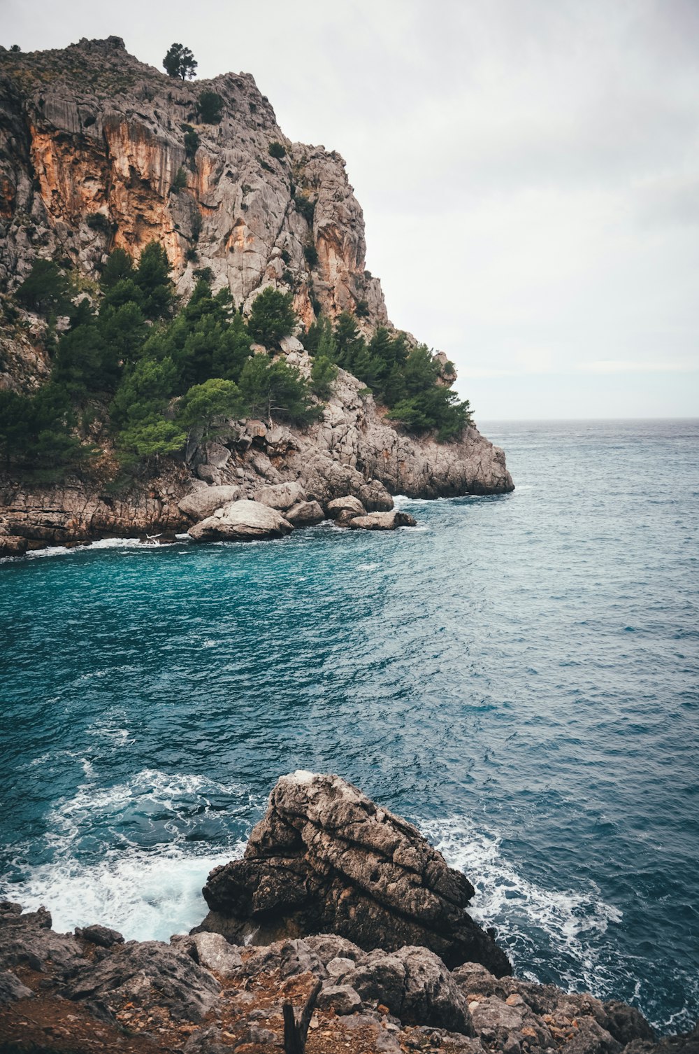 brown rock formation on blue sea under white sky during daytime